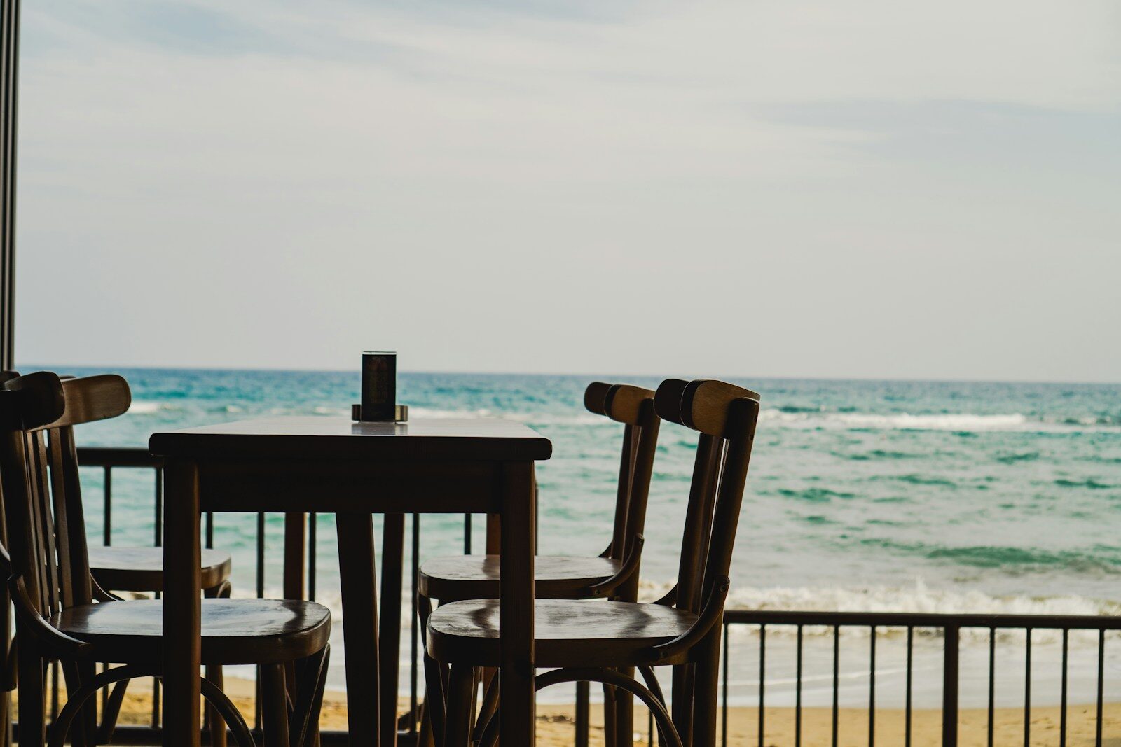Wooden chairs and table on a balcony overlooking the ocean